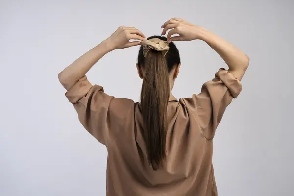 woman-tying-her-hair-back-view